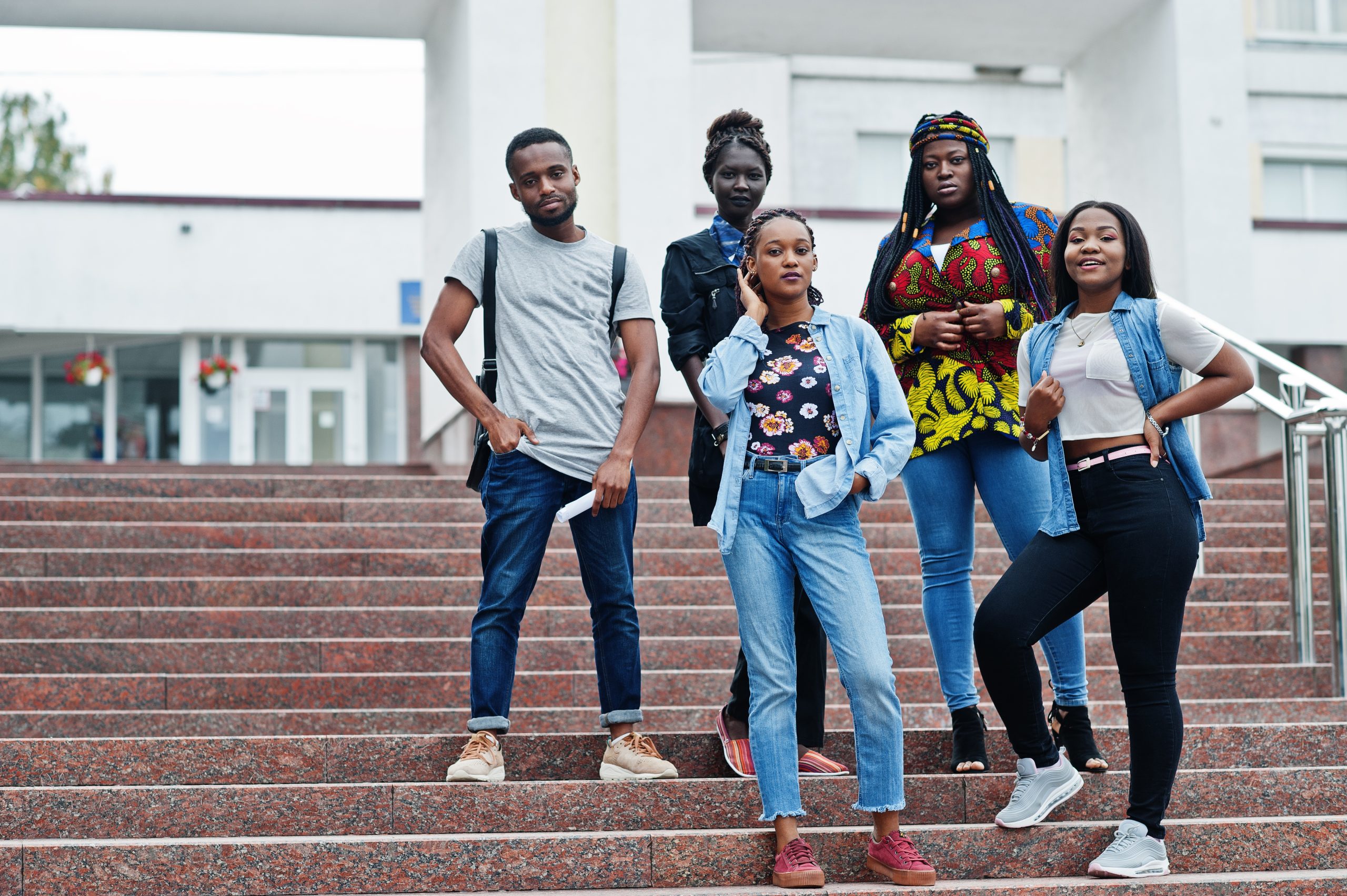 Group of five african college students spending time together on campus at university yard. Black afro friends studying. Education theme.